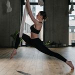 Woman practicing aerial yoga, showcasing strength and balance in a modern studio setting.
