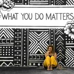 A woman sitting against a motivational mural reading 'What You Do Matters' in Birmingham, AL.