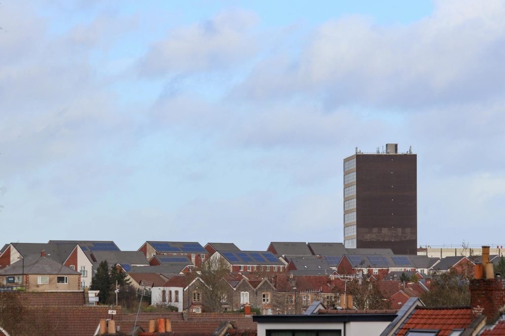 Scenic view of Bristol's urban rooftops featuring solar panels and a tall building.
