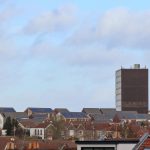 Scenic view of Bristol's urban rooftops featuring solar panels and a tall building.