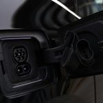 Close-up image of an electric vehicle charging port on a black car.