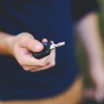 A hand holding a car key outdoors, emphasizing security and control.