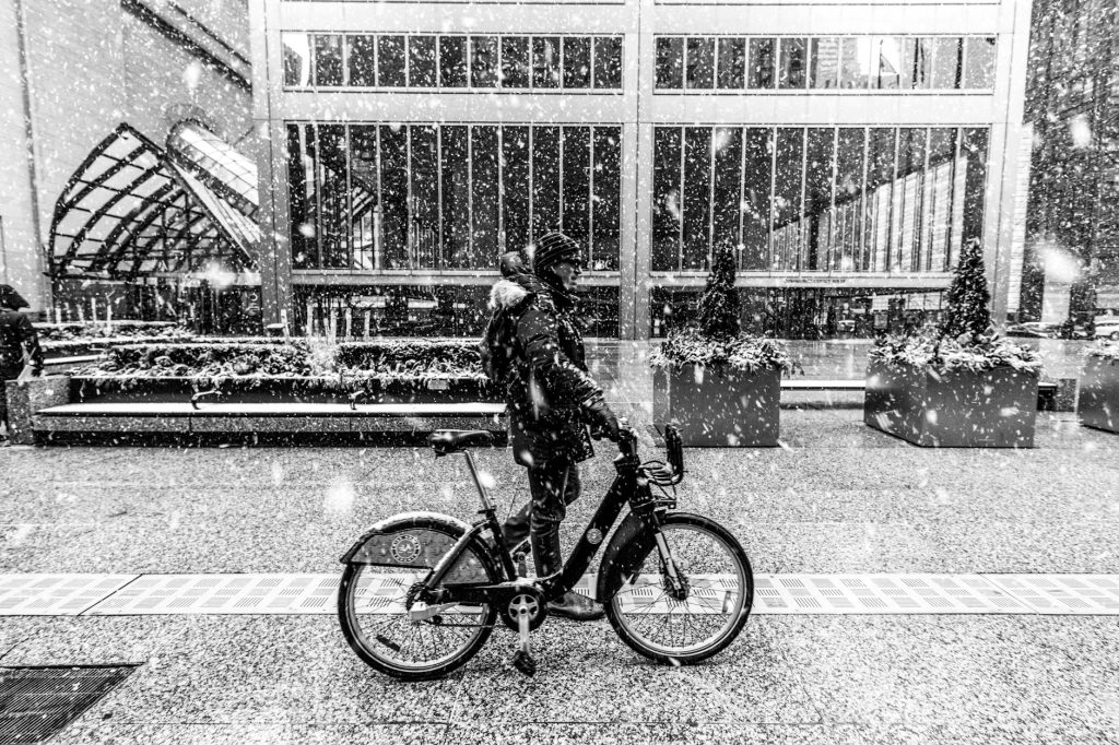 A man rides a bike in a snow-covered downtown Toronto during winter.