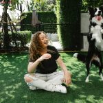 Woman enjoying playful moments with border collie outdoors in summer.