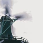 Windmill in motion with blurred blades set against a backdrop of a cloudy sky, symbolizing renewable energy.