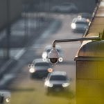 CCTV camera monitoring city traffic on a busy road with blurred vehicles in the background.