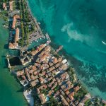 Aerial shot of a coastal town with clear turquoise waters and residential buildings.