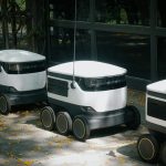 Autonomous delivery robots on a sidewalk during daytime, showcasing modern technology.