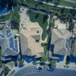 Aerial view of suburban houses featuring solar panels and green lawns, symbolizing eco-friendly living.