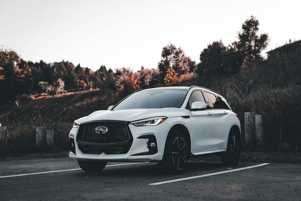 A sleek white SUV parked in an outdoor setting during sunset, surrounded by nature.