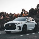 A sleek white SUV parked in an outdoor setting during sunset, surrounded by nature.