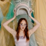 Stylish young woman in futuristic setting holding a cosmic themed accessory.