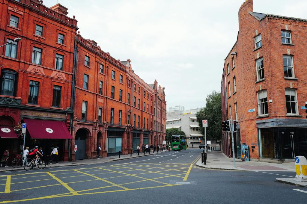 A bustling urban street with red brick buildings and a green bus passing by.