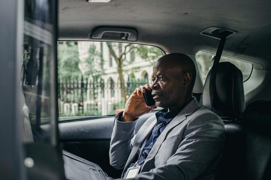 African American businessman in a suit having a phone conversation while traveling in a car in an urban setting.