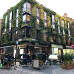 Victorian building with vertical garden facade in busy London street.