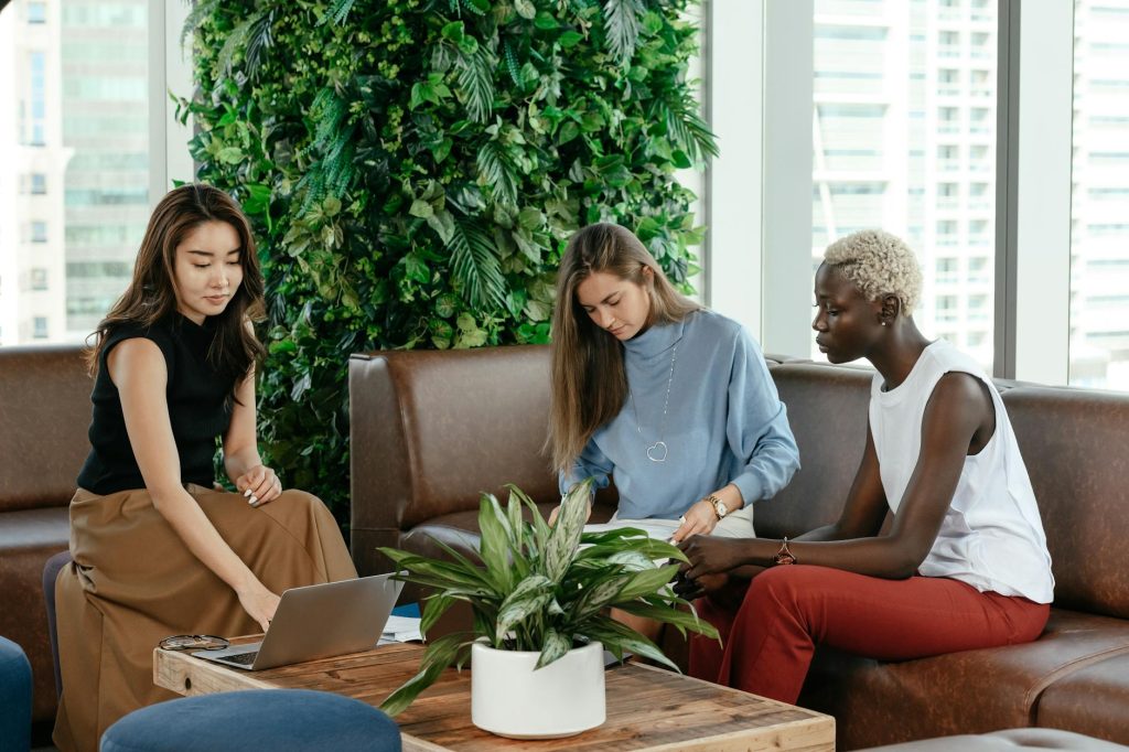 Group of diverse professionals collaborating in a bright, modern office setting with green plants.